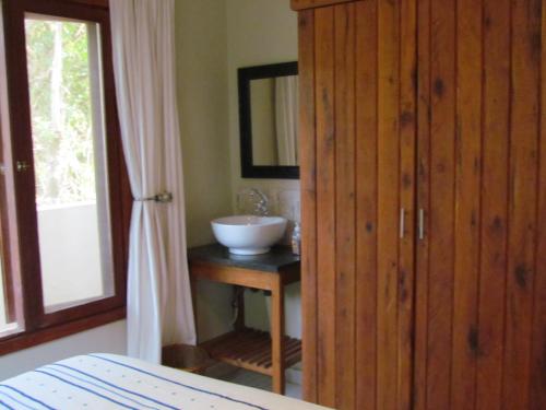 a bathroom with a sink and a wooden cabinet at Nkumbe Bush Retreat Family Home in Ponta Malongane