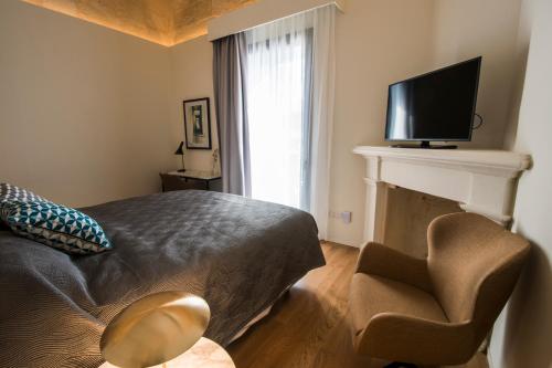 a bedroom with a bed and a television and a chair at Cugo Gran Macina Malta in Senglea