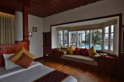 Una sala de estar con dos camas y una ventana. en SpiceTree Munnar, en Chinnakanal