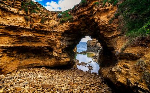 an arch in the rocks next to the ocean at Seahorse Coastal Villas in Peterborough