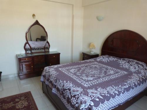 a bedroom with a bed and a dresser and a mirror at Mountain View Apartments in Luxor