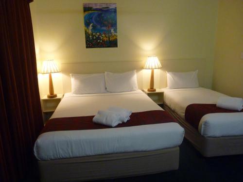 a hotel room with two beds and two lamps at International Lodge Motel in Mackay