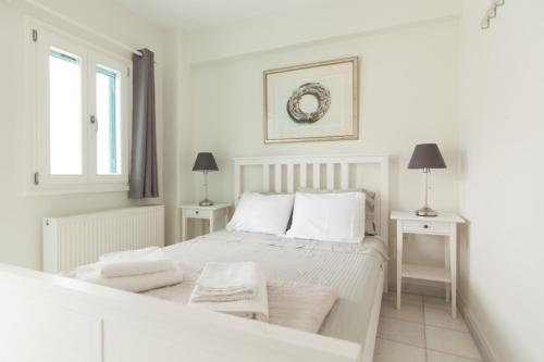a white bedroom with a white bed and two tables at PEBBLES 1BD house with Sea View in the heart of Naousa in Naousa