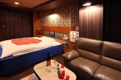 a bedroom with a bed and a couch and a table at Hotel Kyoto (Adult Only) in Zentsuji