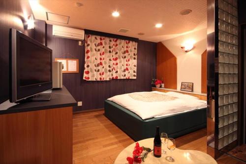 a bedroom with a bed and a flat screen tv at Hotel Kyoto (Adult Only) in Zentsuji