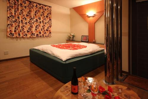 a bedroom with a bed and a table with a bottle of wine at Hotel Kyoto (Adult Only) in Zentsuji
