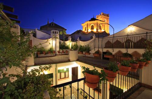 a building with potted plants on a fence at night at Casa Baños de la Villa in Priego de Córdoba