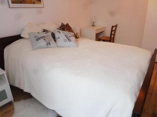 una camera da letto con un letto bianco e cuscini sopra di Les Marronniers a La Chapelle-sous-Brancion