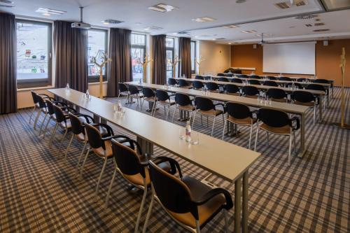 a conference room with rows of tables and chairs at Wellness Hotel Montis in Mozirje