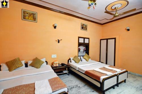 ジャイサルメールにあるHotel Jaisal Palaceのオレンジ色の壁の部屋にベッドが2つある