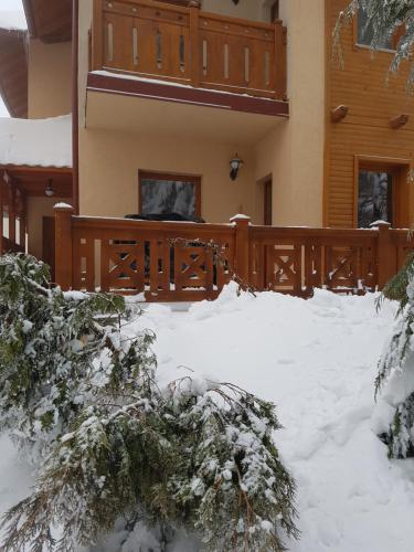 a house with a fence in the snow at Apartment Joksimovic in Zlatibor