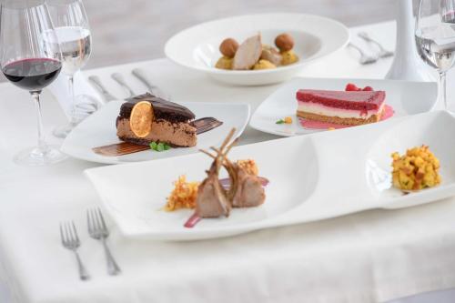 a table with plates of food and glasses of wine at Wellness Hotel Montis in Mozirje