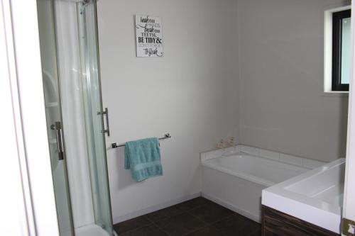 a bathroom with a shower and a tub and a sink at Between the Mountains in Rotorua