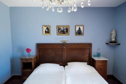 um quarto com uma cama com lençóis brancos e um lustre em B&B Candelária em Loulé