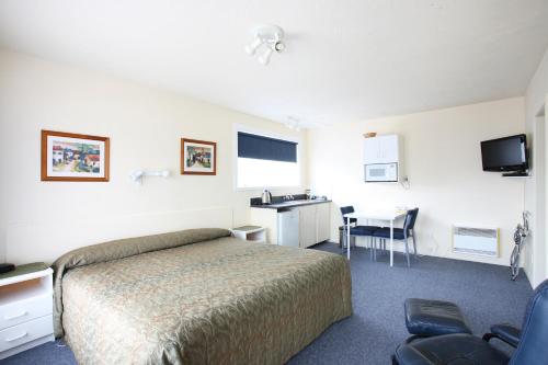 a hotel room with a bed and a desk and a sink at Queens Park Motels in Invercargill