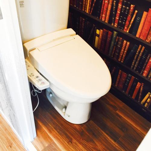 a white toilet sitting in a room with books at Guest House Fukuoka W301 in Kasugabaru