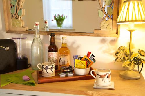 a shelf with bottles and cups on a table at The Coach House in Rudgwick