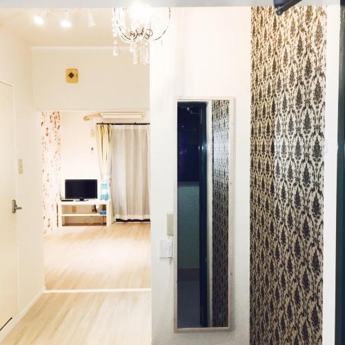 a hallway with a mirror and a living room at Guest House Fukuoka W302 in Kasugabaru