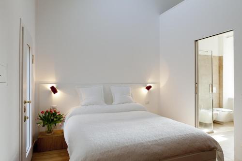 ein weißes Schlafzimmer mit einem großen Bett und einem Spiegel in der Unterkunft Parco Sempione in Mailand