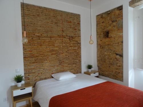 a bedroom with a brick wall and a bed at Alojamentos Casa Facha Papaia in Portalegre