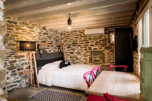 a bedroom with a bed and a stone wall at Imarkellis Boutique Villas in Pánormos