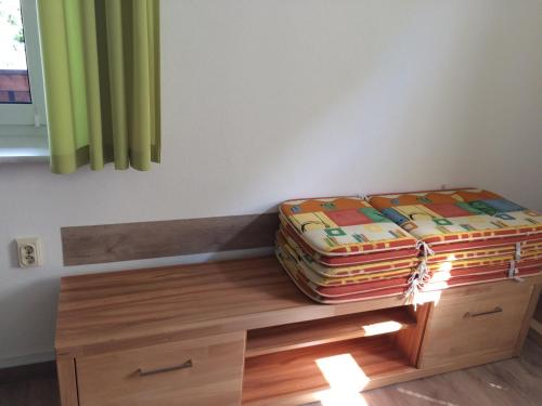 a bed sitting on a wooden bench under a window at Pension Hönel-Hof Bad Schandau in Bad Schandau