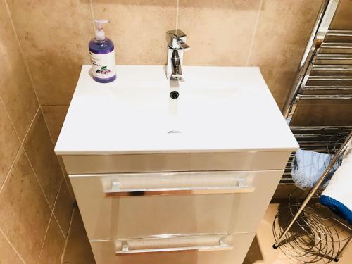 a bathroom with a white sink with a soap bottle on it at Wynchlands 4 Bedroom House in St Albans City in Saint Albans