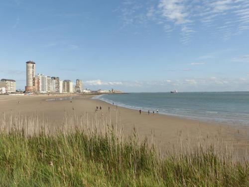 a beach with people walking on the sand and the ocean at Bellevue Boulevard 32 in Vlissingen