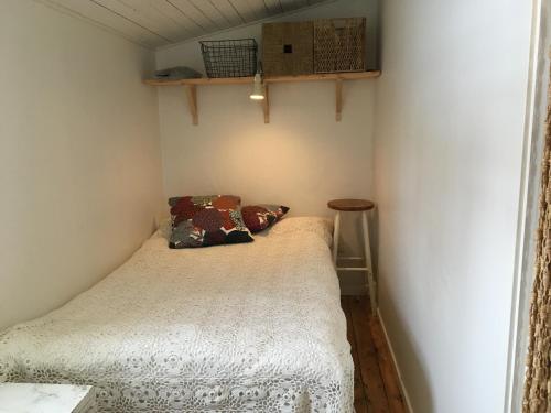 Dormitorio pequeño con cama con almohadas en Tråvad Nybo Lilla huset en Tråvad