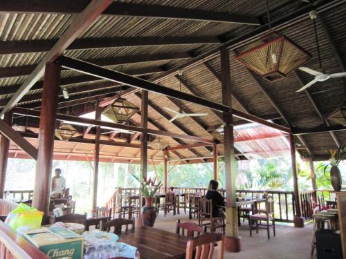 Phanom Bencha Mountain Resort في مينْغكرابي: مطعم بالطاولات والكراسي والناس جالسين على الطاولات