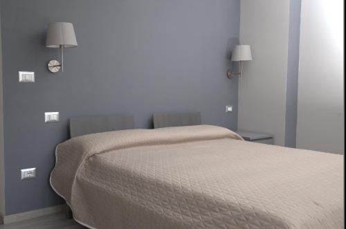 a bed in a bedroom with two lights on the wall at Agriturismo Il Parco in Nusco