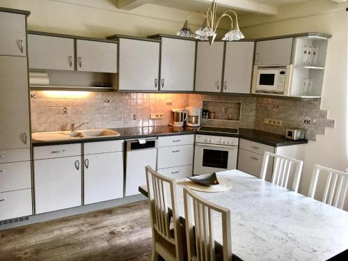 a kitchen with white cabinets and a table with chairs at Ferienwohnungen Panorama Harrys Bike Tours in Villach