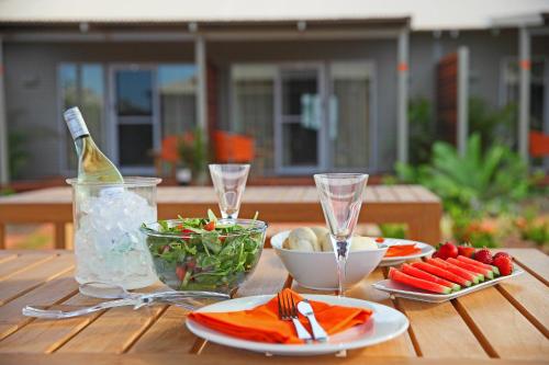 a wooden table with plates of food and a bottle of wine at Best Western Plus The Ranges Karratha in Karratha