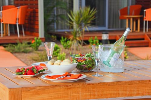a wooden table with food and a bottle of wine at Best Western Plus The Ranges Karratha in Karratha