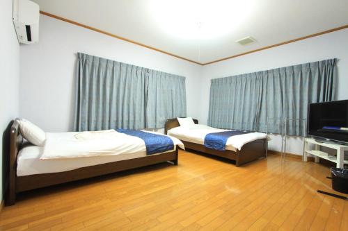 Una habitación de hotel con dos camas y un televisor de pantalla plana. en 白浜オーシャンヴィラ, en Shirahama