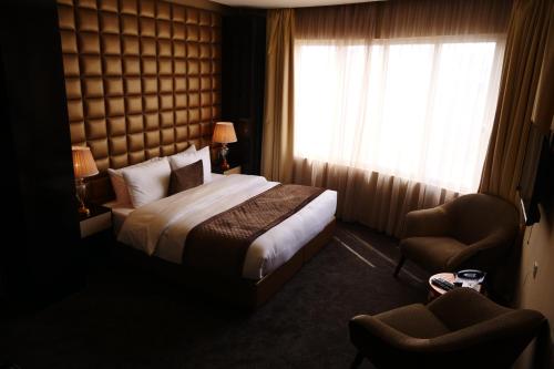 a bedroom with a bed and a window and a chair at Lumiere Des Etoile in Kuwait