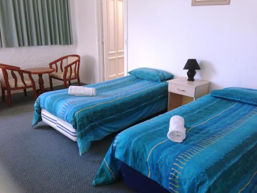 um quarto de hotel com duas camas e uma mesa e cadeiras em Aquarius Resort em Merimbula