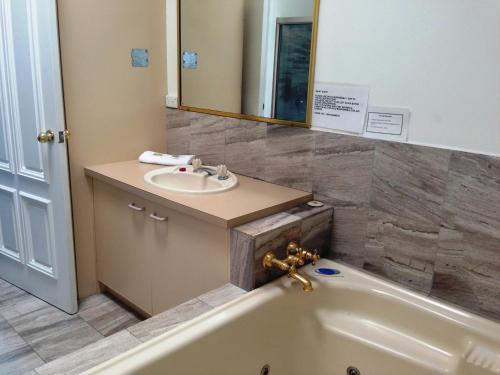 a bathroom with a tub and a sink and a mirror at Aquarius Resort in Merimbula