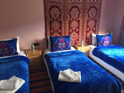 two beds in a room with blue sheets and blue pillows at Puerta Azul in Chefchaouene