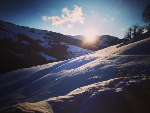 a snow covered hill with the sun in the background at Ferienwohnung Klappacher in Maria Alm am Steinernen Meer