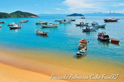 a group of boats in the water near a beach at Pousada Palmares in Cabo Frio
