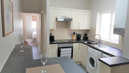 a kitchen with two wine glasses on a counter at Swindon Home from Home 2 - EnterCloud9SA in Swindon