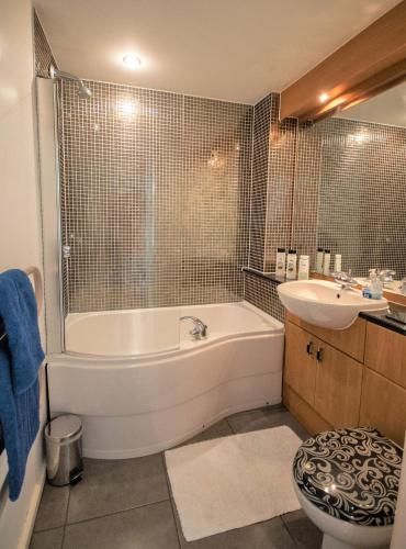 a bathroom with a tub and a sink at Coastal Apartments - Wales in Swansea