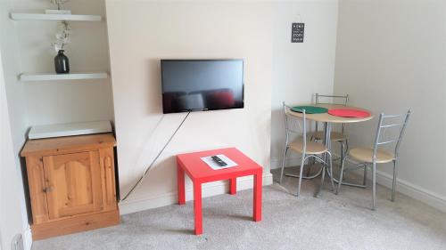 Habitación con mesa roja y TV en la pared. en Swindon City Centre Duplex - EnterCloud9SA en Swindon