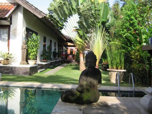a statue sitting next to a swimming pool at Puri Ayu in Canggu