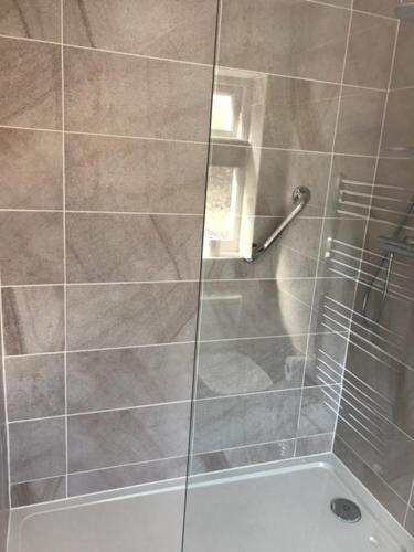 a bathroom with a shower with a glass door at Bromwell Court in Llandudno