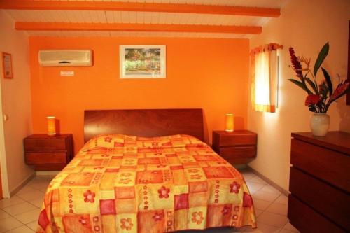 um quarto com uma cama com uma parede laranja em Fleurs des Iles em Deshaies