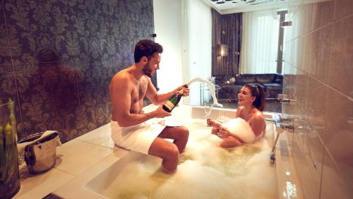 a man and a woman sitting in a bathtub playing at WestCord Fashion Hotel Amsterdam in Amsterdam