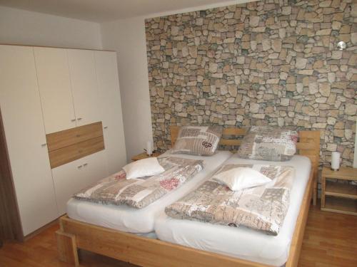 two twin beds in a room with a stone wall at Ferienwohnung Iris Schumacher in Simmerath