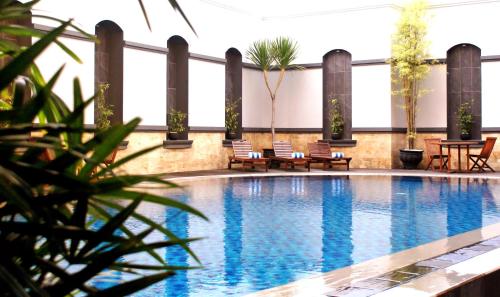 a swimming pool with chairs and tables in a building at Swiss-Belhotel Borneo Samarinda in Samarinda
